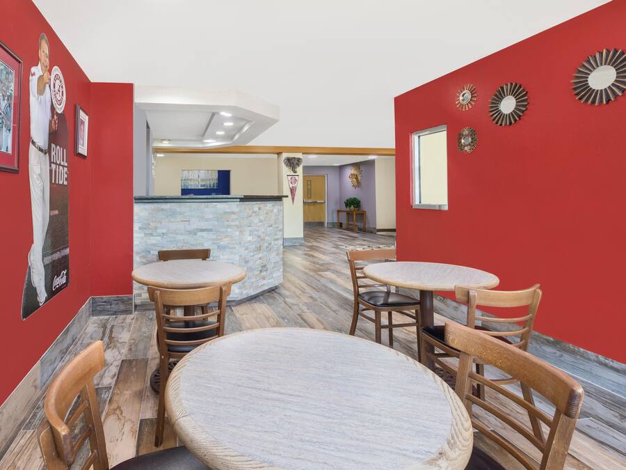A restaurant with red walls, wooden tables, and chairs. There are posters on the walls and a counter in the background.