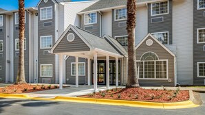 A multi-story hotel with a covered entrance, palm trees, and a landscaped area. - Sleep Inn & Suites Tallahassee-Capitol (Tallahassee)