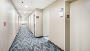 A hotel hallway with a patterned carpet, beige walls, and doors numbered 2 and 3. - Sleep Inn & Suites Tallahassee-Capitol (Tallahassee)