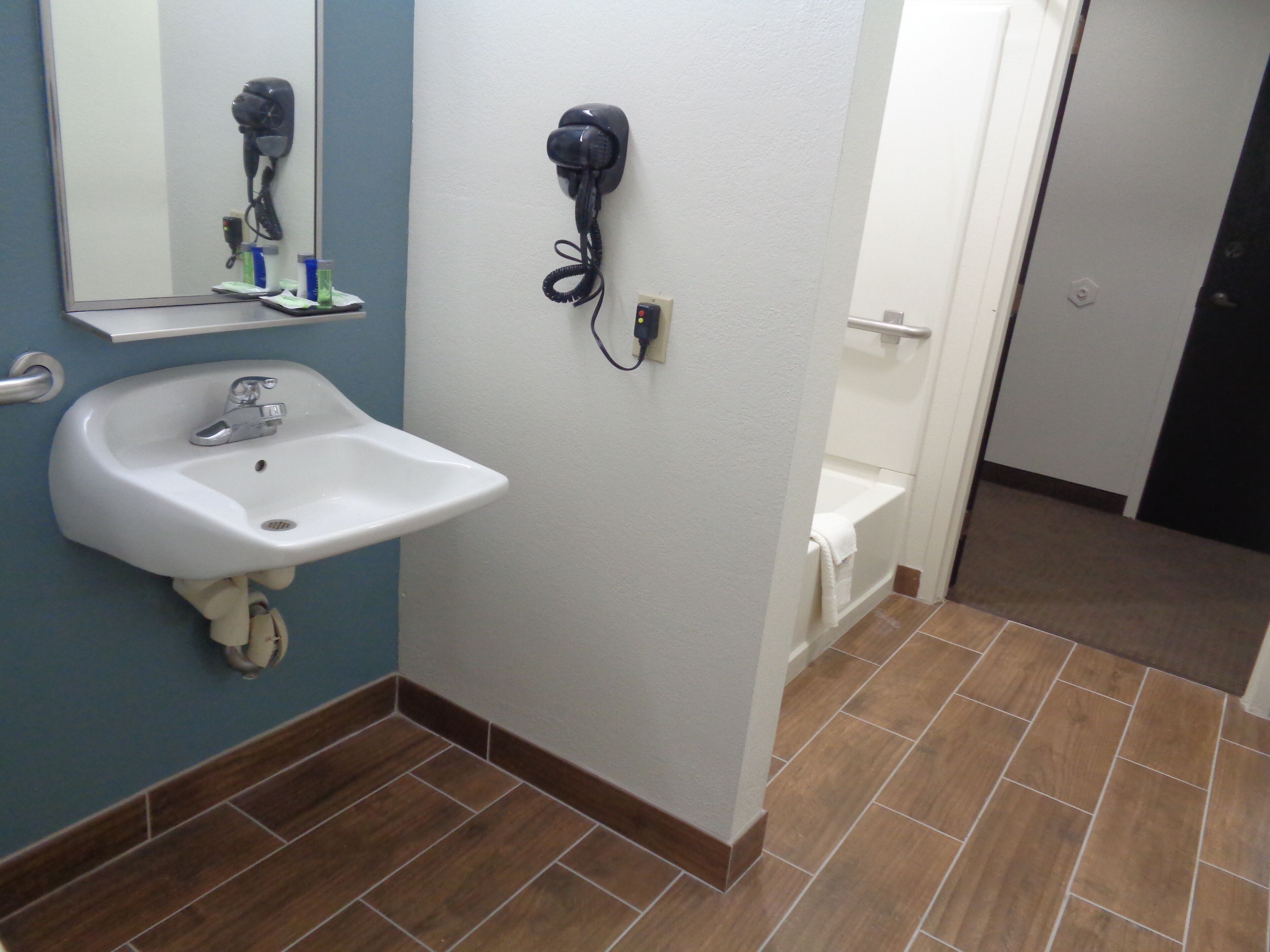 A bathroom with a white sink, a hairdryer, and a telephone mounted on the wall.