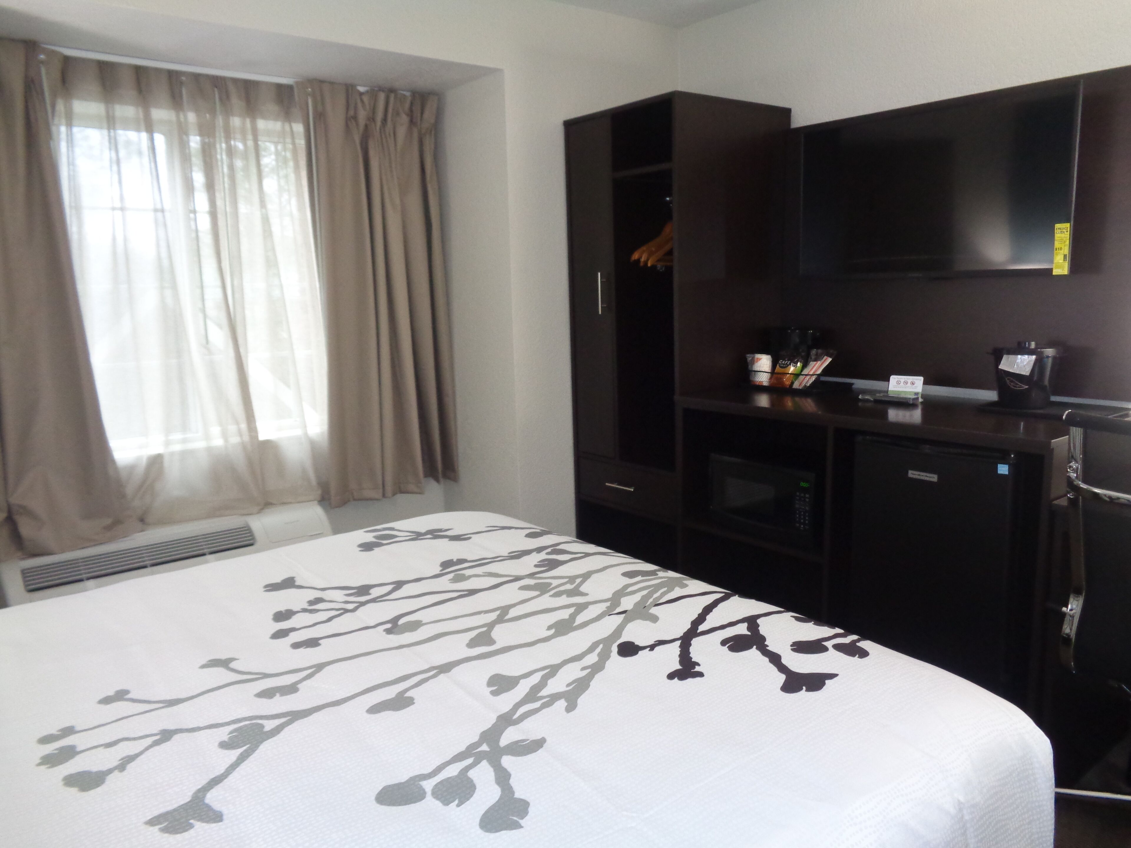 A hotel room with a bed, a wardrobe, a TV, and a microwave.