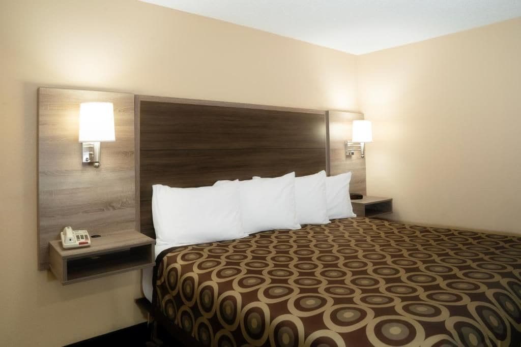 Una habitación de hotel con una cama grande, dos mesitas de noche y lámparas de pared.