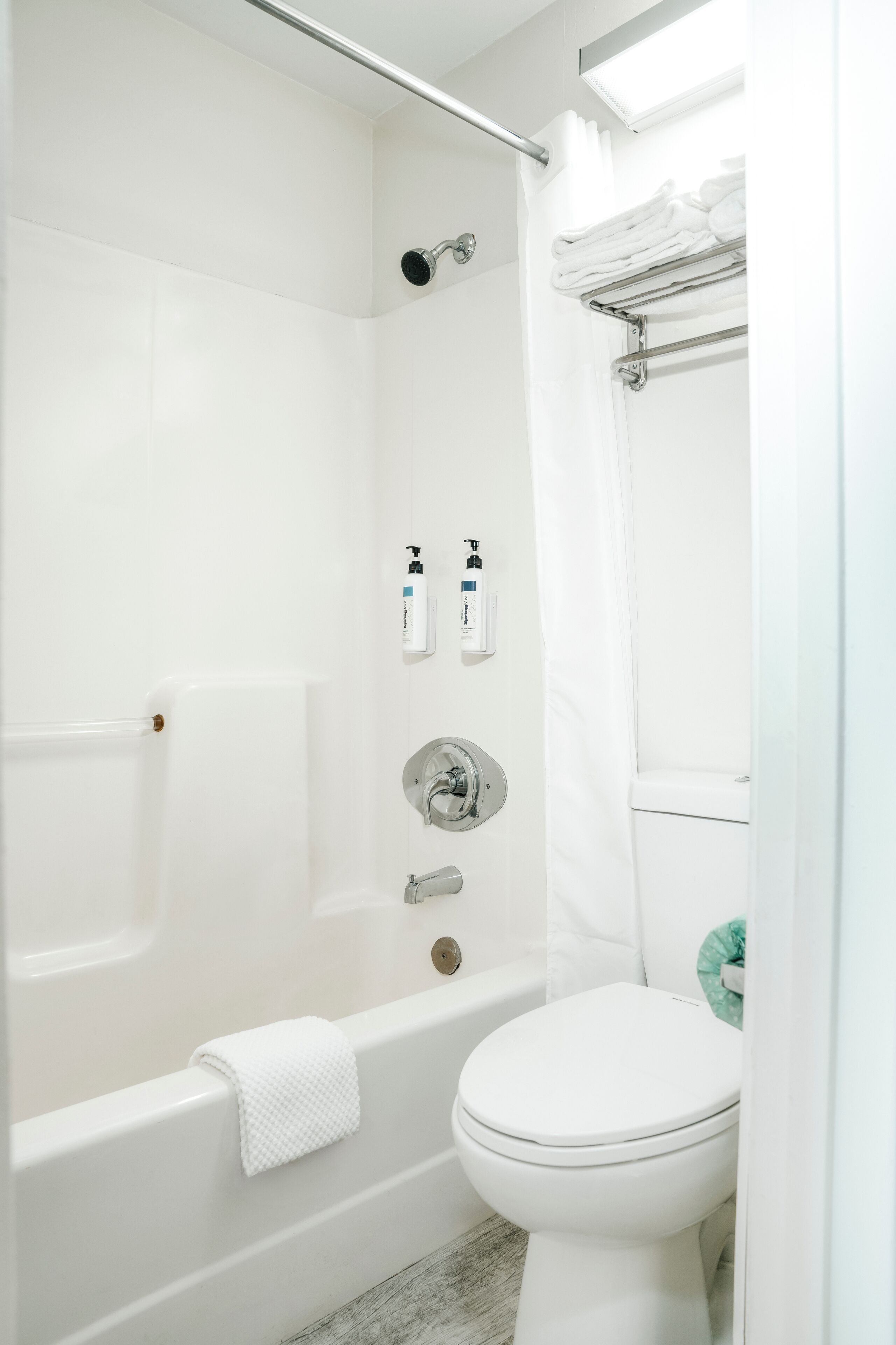 A modern bathroom with a bathtub, toilet, and shower area.