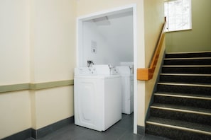 A laundry area with two white washing machines, a wooden staircase, and a door leading to another room. - Guest Inn Pigeon Forge (Pigeon Forge)