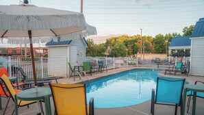 A swimming pool area with chairs and umbrellas, surrounded by a fence.
