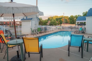 A swimming pool area with chairs and umbrellas, surrounded by a fence. - Guest Inn Pigeon Forge (Pigeon Forge)