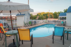 A swimming pool area with chairs and umbrellas, surrounded by a fence.