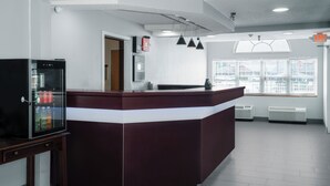 A reception area with a counter, a refrigerator, and a window with blinds.