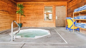 A wooden cabin with a hot tub, a door, and a shelf with towels. - Comfort Inn Worland Hwy 16 to Yellowstone (Worland)