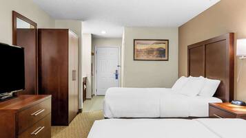 Una habitación de hotel con una cama, televisión, cómoda y un cuadro en la pared.