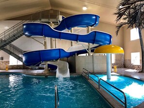 An indoor water park with multiple blue slides and a pool.