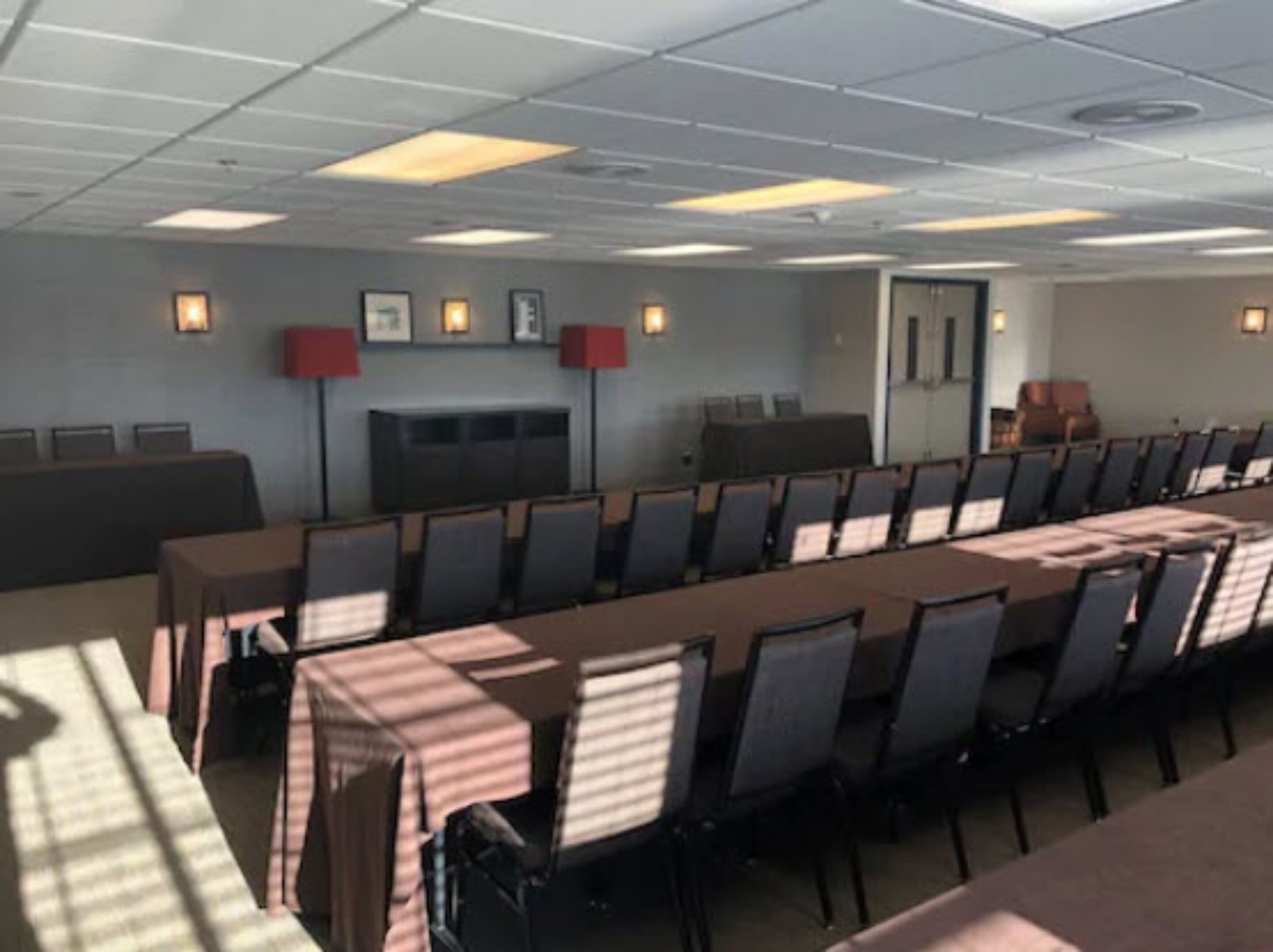 Une salle de conférence avec une longue table et des chaises, une cheminée et des tableaux encadrés accrochés au mur.