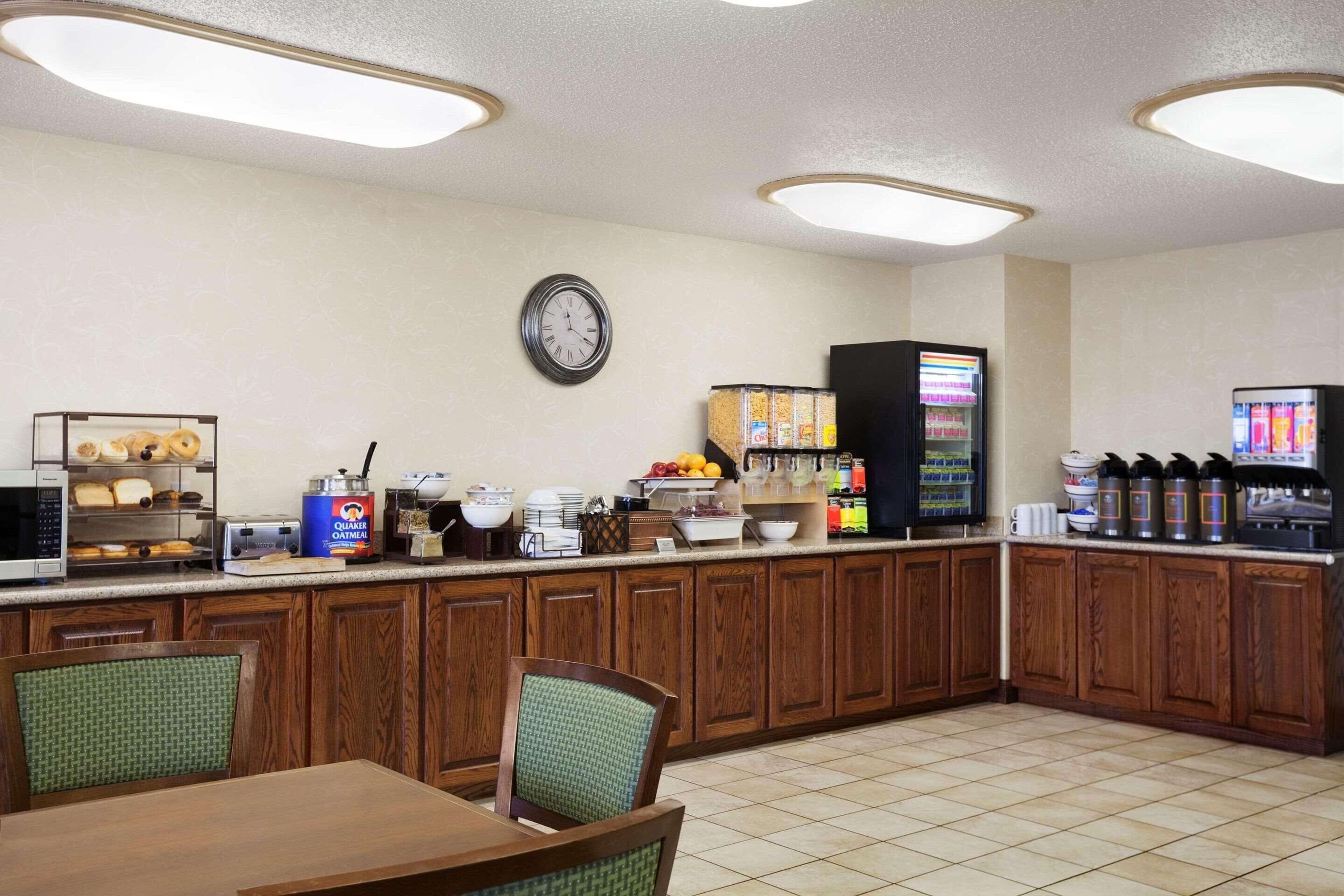 A breakfast bar with a clock, a microwave, a toaster, and a coffee machine.
