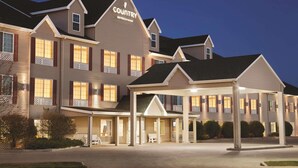A Country Suites hotel with a covered entrance, multiple balconies, and a well-lit facade. - Country Inn & Suites by Radisson Bismarck Waterpark (Bismarck)