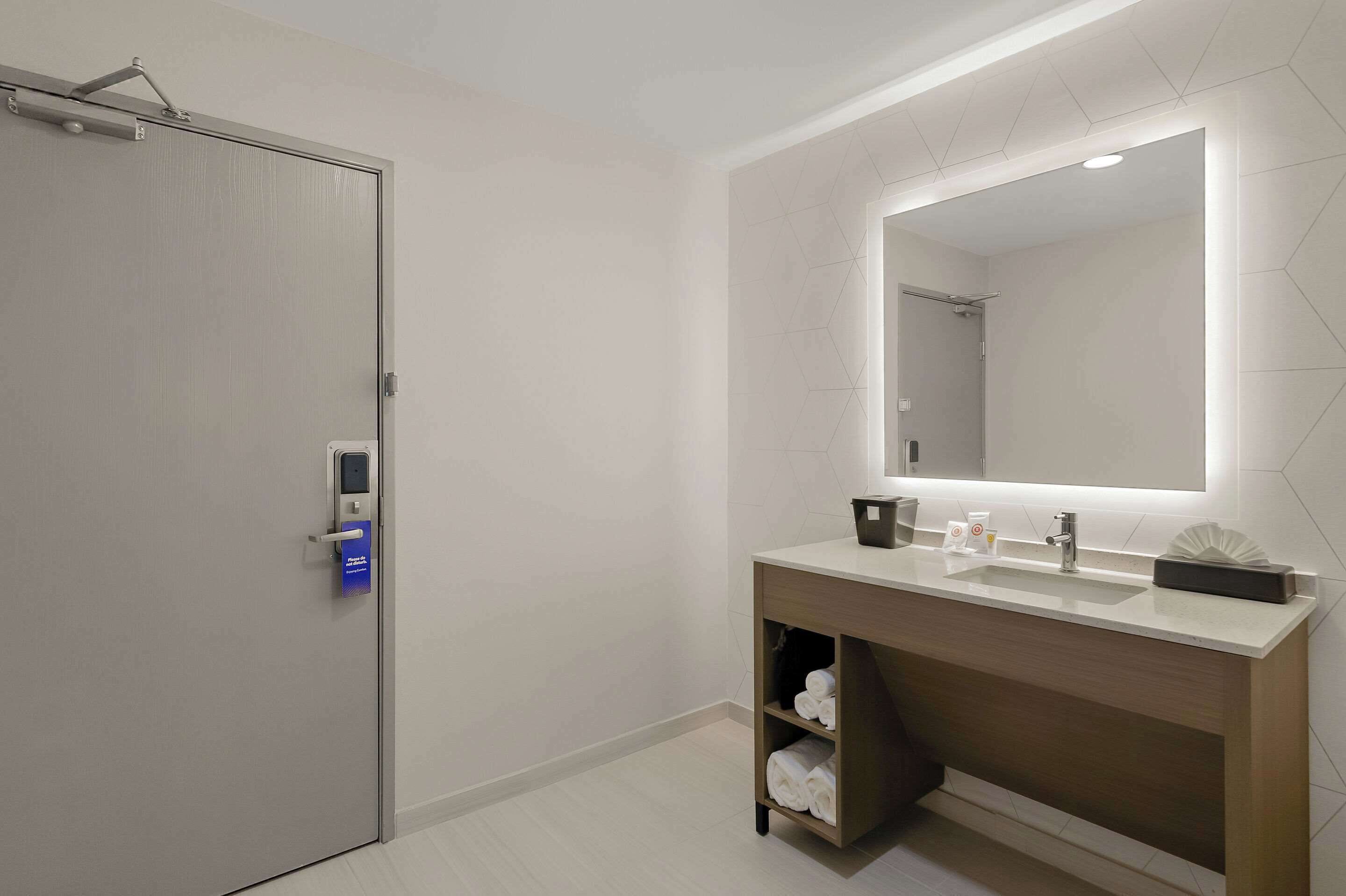 Une salle de bain moderne avec un grand miroir, un lavabo et un porte-serviettes.