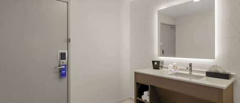 Une salle de bain moderne avec un grand miroir, un lavabo et un porte-serviettes.