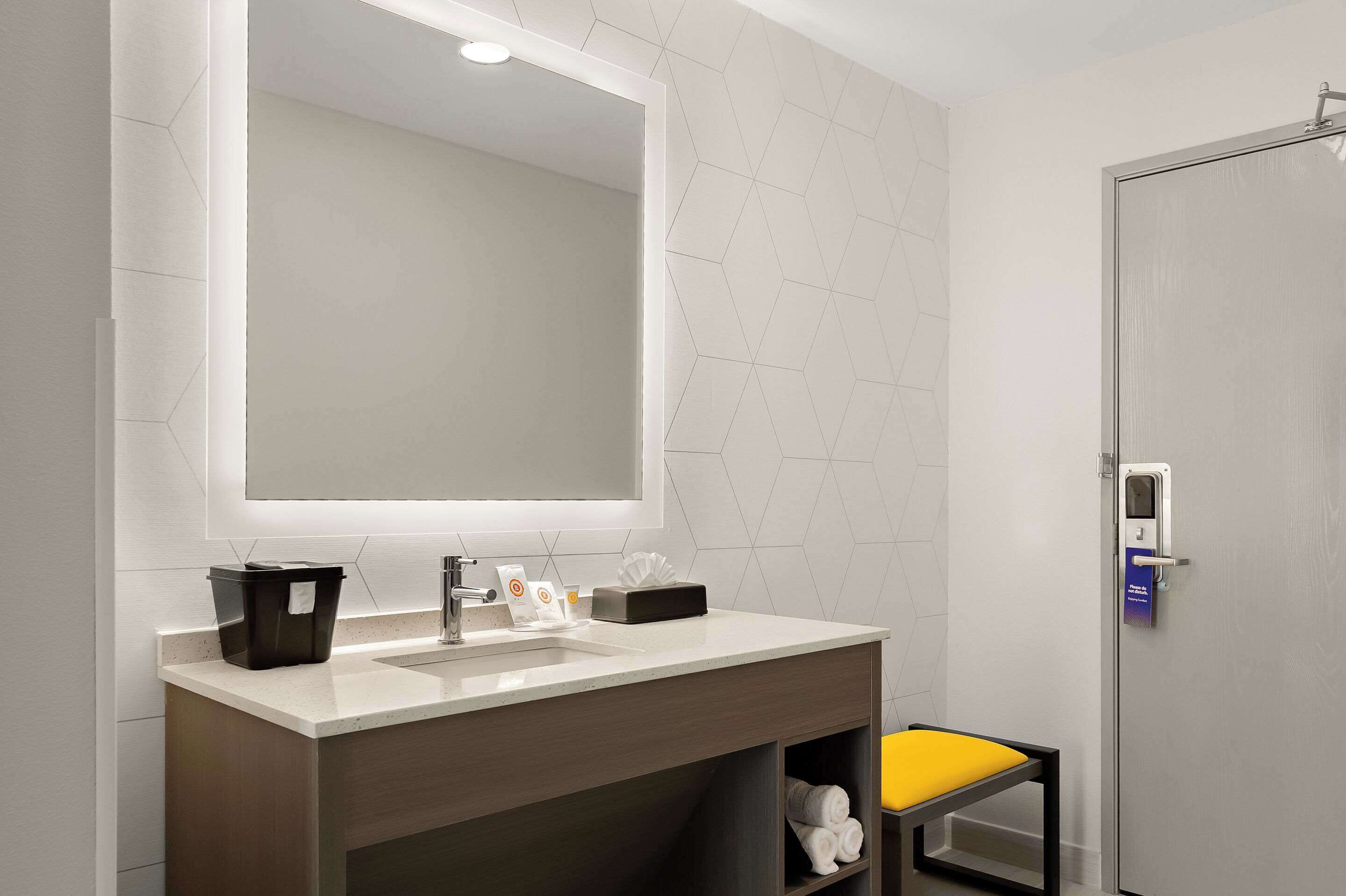 A modern bathroom with a large mirror, two sinks, a toilet, and a shower.