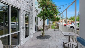 Un espace extérieur aménagé en terrasse, avec un sol en pierre, des sièges et un arbre.