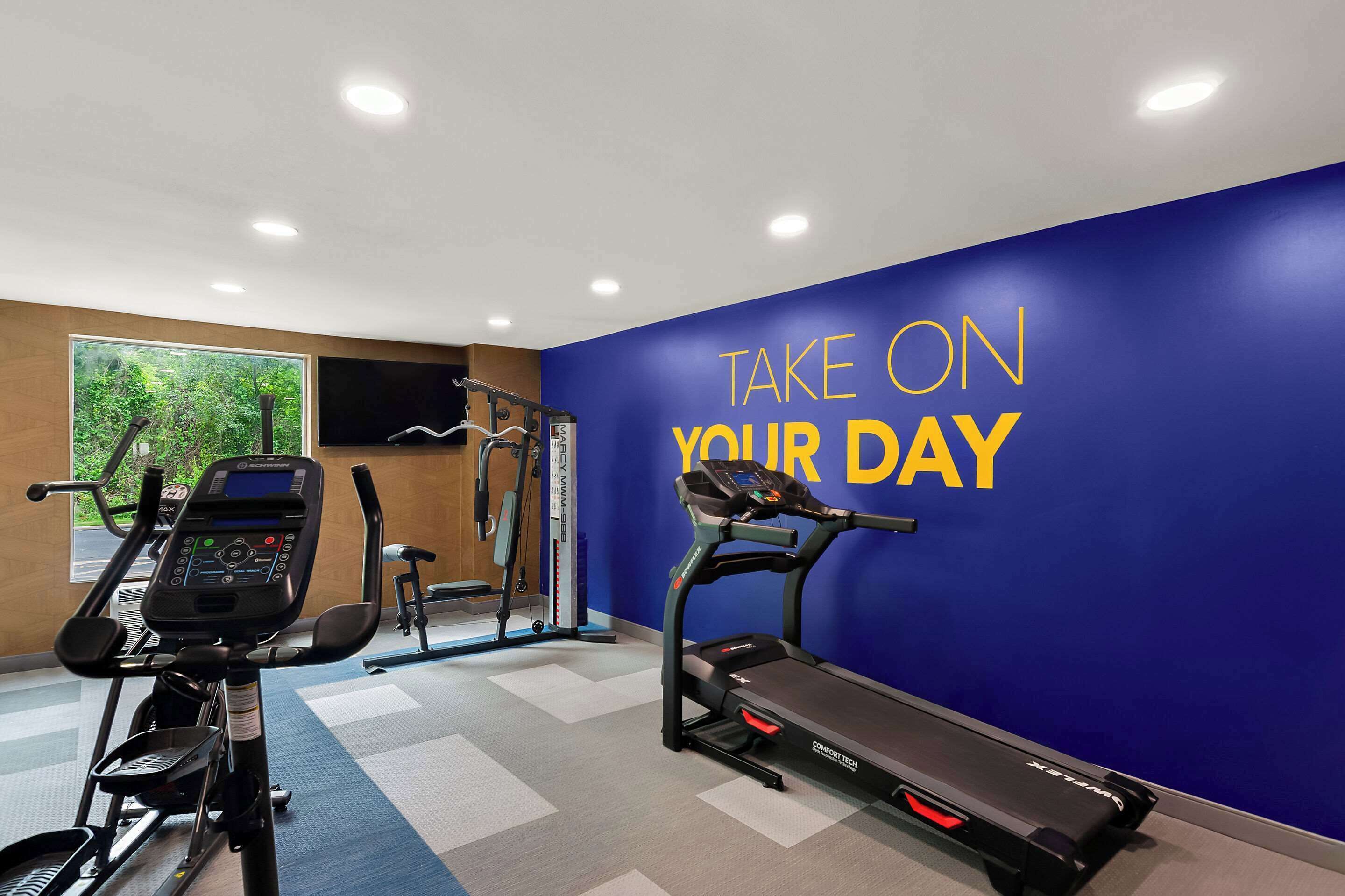 A gym with treadmills, elliptical machines, and a wall with motivational text.