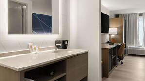 Une salle de bain d’hôtel avec un grand miroir, un lavabo, des toilettes et un espace douche.