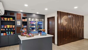 Un bar proposant des collations, avec des étagères remplies de divers produits emballés, un présentoir réfrigéré et un comptoir où l’on trouve de l’eau en bouteille et des en-cas.