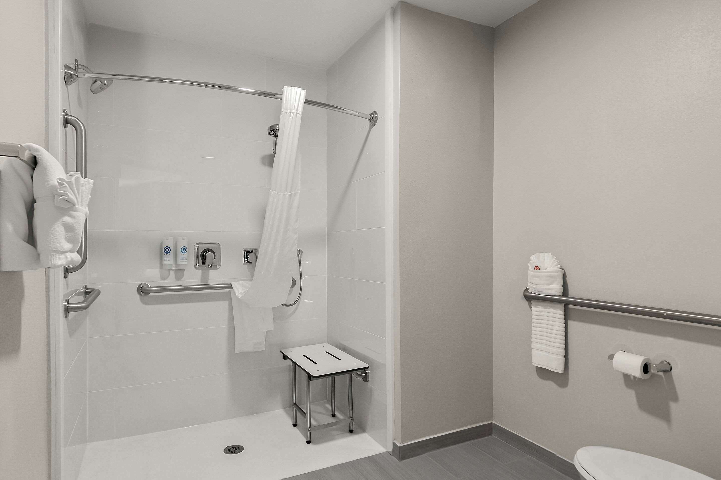 Et moderne badeværelse med brusebad, gelænder, et lille bord og toilet.