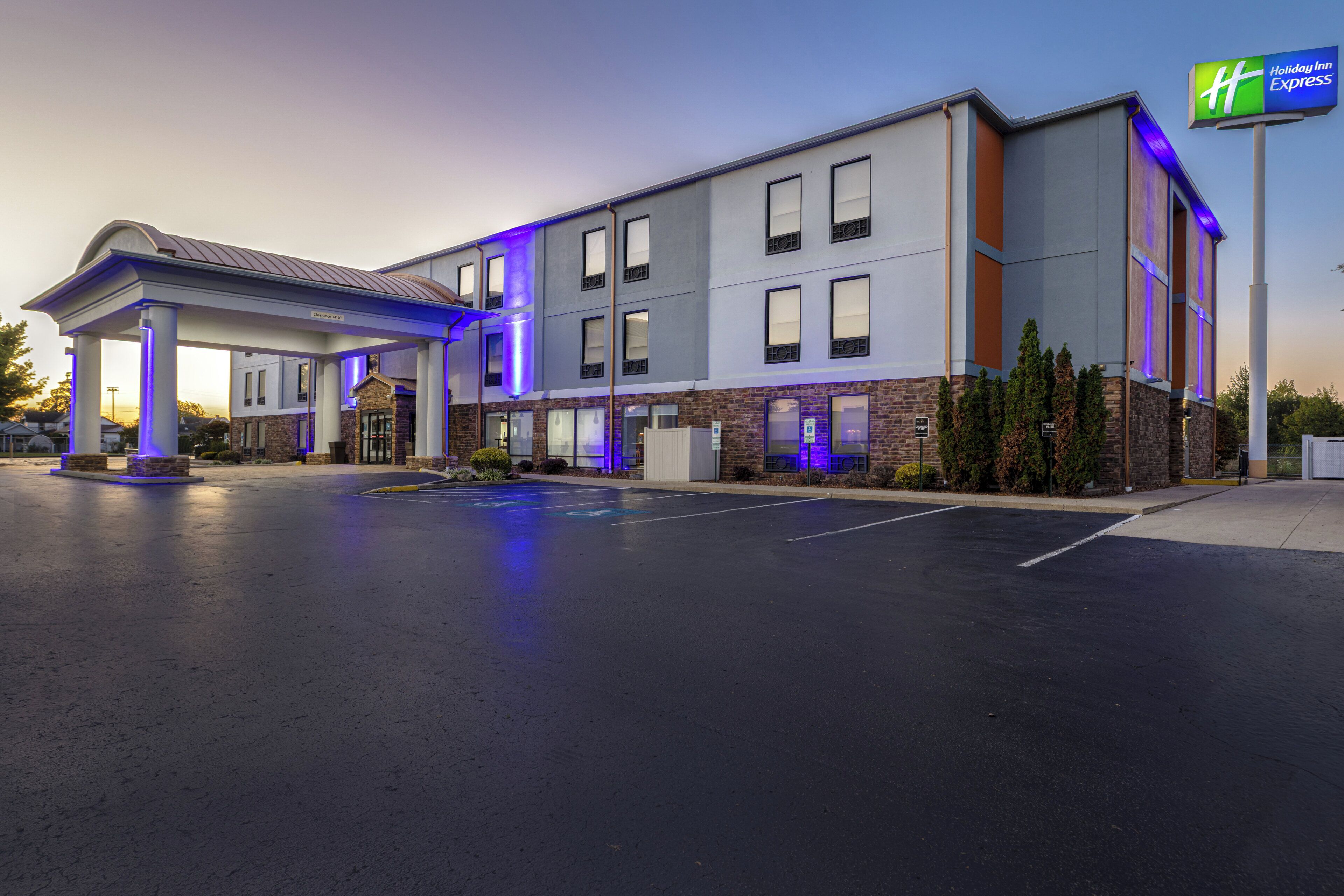 Edificio de Holiday Inn Express con entrada cubierta, estacionamiento y cielo despejado.