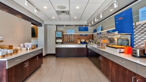 A modern breakfast area with a central counter, various food stations, and a bakery section. - Holiday Inn Express Chillicothe East by IHG (Chillicothe)