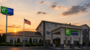 Un bâtiment de l’hôtel Holiday Inn Express offrant une vue dégagée sur l’entrée, le drapeau et la végétation environnante.