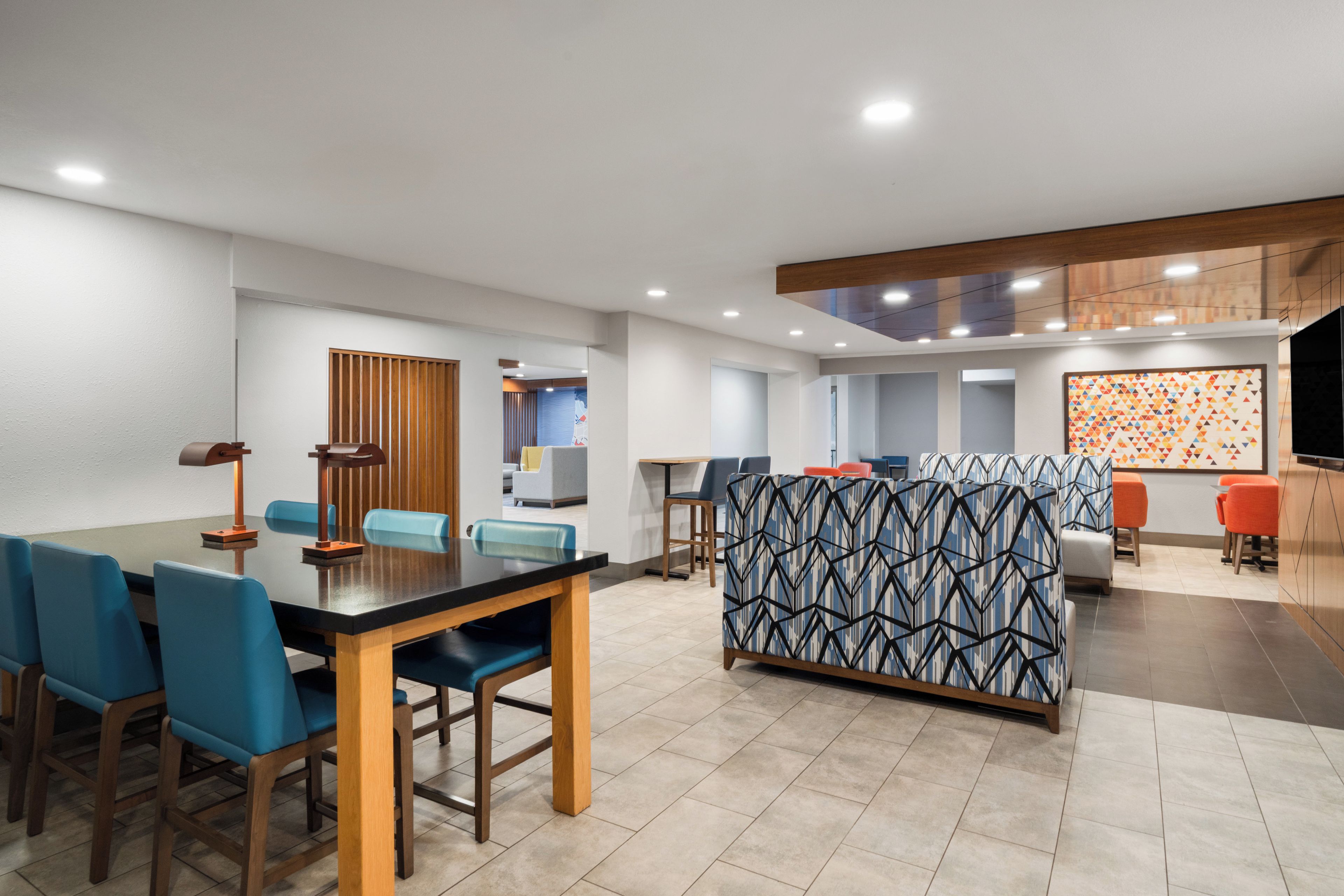 A modern hotel lobby with a dining area, seating arrangements, and a reception desk.