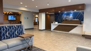 Un hall d’hôtel comprenant un comptoir d’accueil, un espace salon et un écran de télévision.