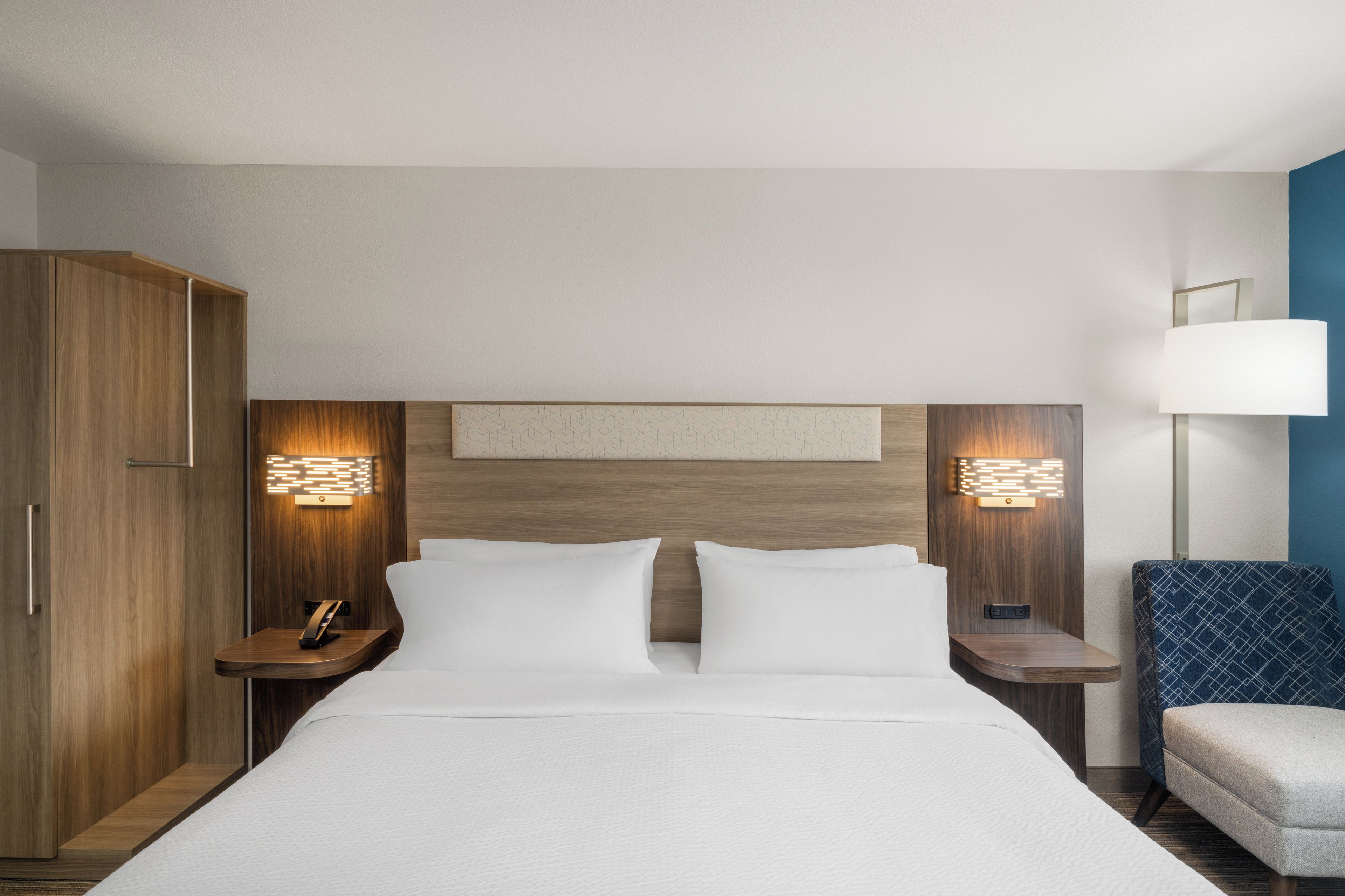 Una camera d'albergo con un letto, due comodini, un armadio e una lampada.