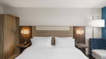 A hotel room with a bed, two bedside tables, a wardrobe, and a lamp.