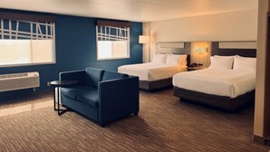 Une chambre d’hôtel avec deux lits, un canapé, une fenêtre donnant sur un beau paysage et une lampe fixée au mur.