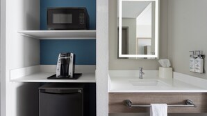 A modern bathroom with a white sink, a mirror, a towel rack, and a coffee machine on a shelf. - Holiday Inn Express Harrisburg I-81 – Hershey by IHG (Harrisburg)
