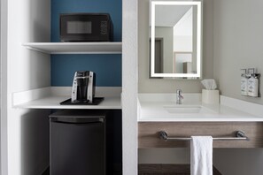 A modern bathroom with a white sink, a mirror, a towel rack, and a coffee machine on a shelf. - Holiday Inn Express Harrisburg I-81 – Hershey by IHG (Harrisburg)