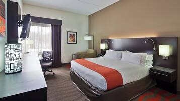 A hotel room with a bed, desk, chair, and two bedside lamps.