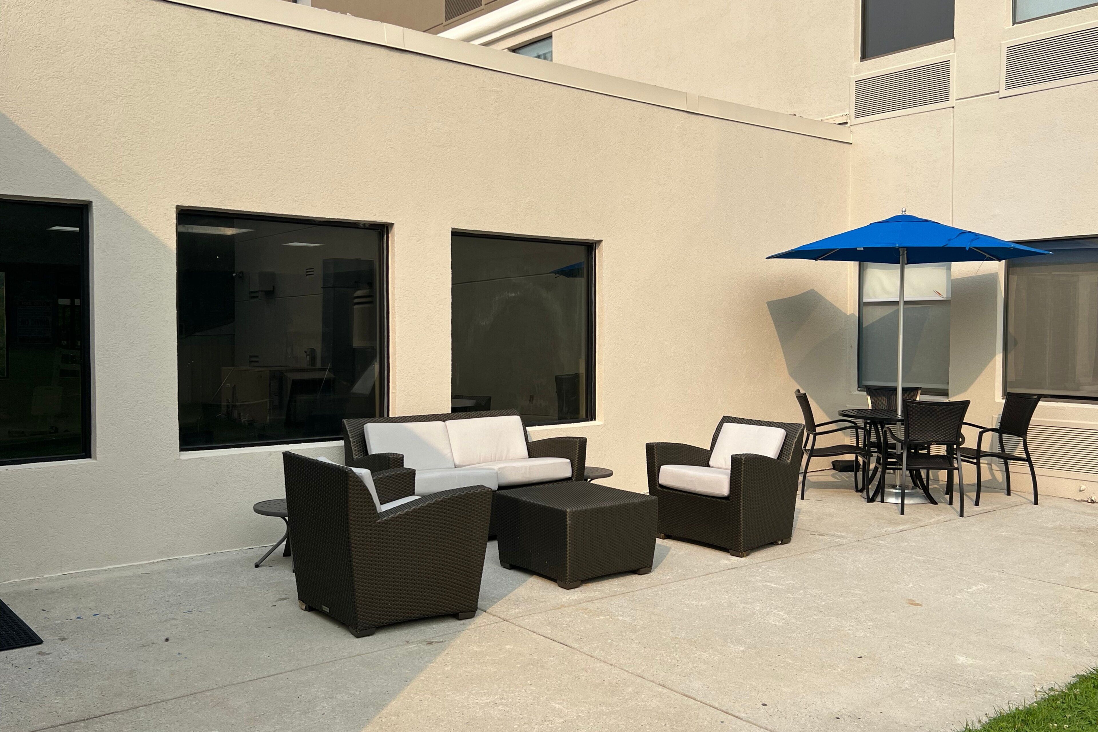 An outdoor seating area with wicker furniture and a blue umbrella.