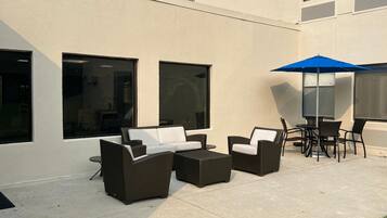 An outdoor seating area with wicker furniture and a blue umbrella.