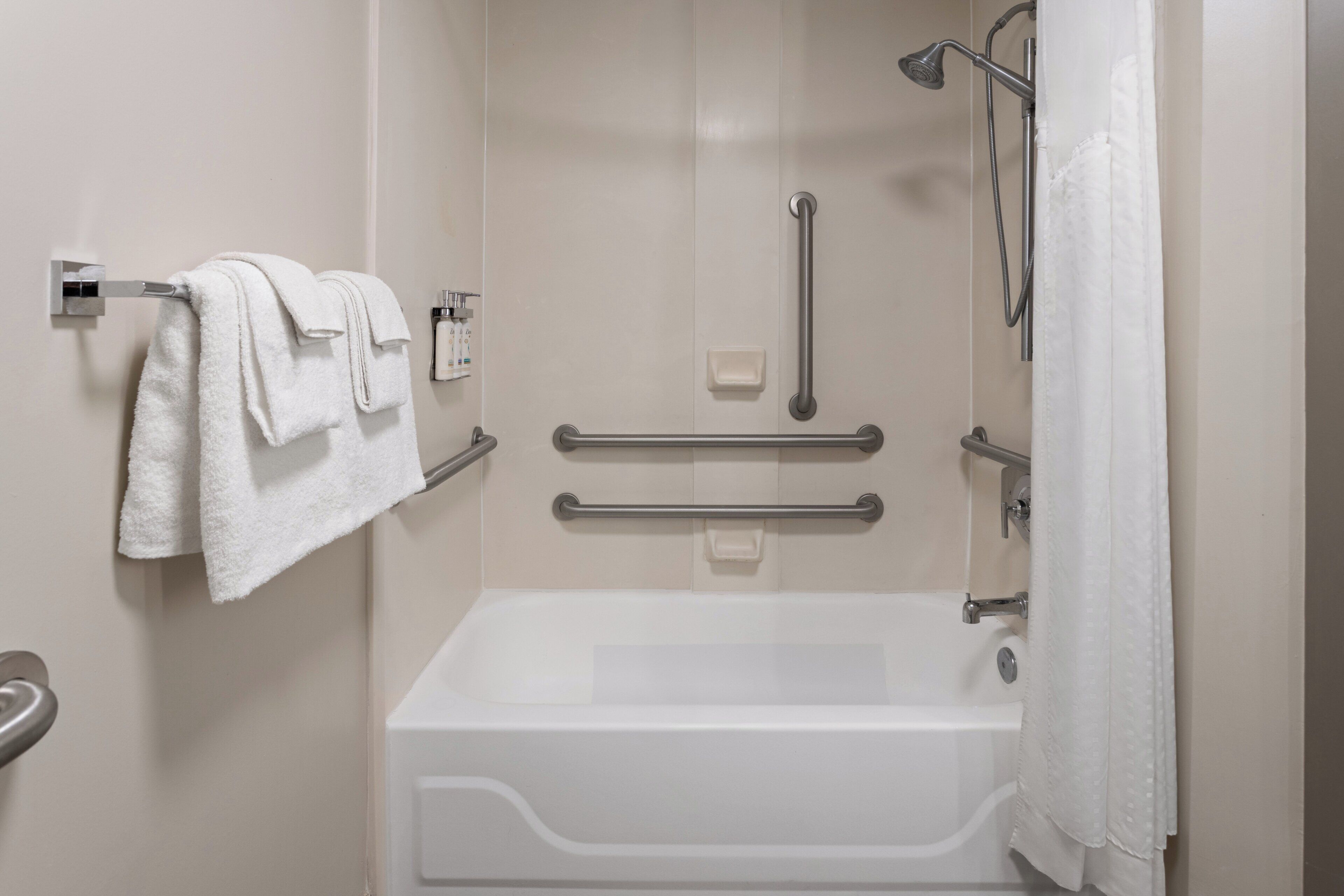 Ein modernes Badezimmer mit Badewanne, Haltegriffen und Handtuchhalter.