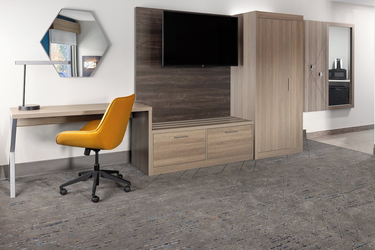 A modern office space with a desk, chair, and built-in TV.