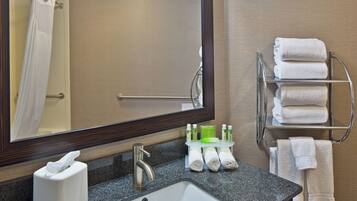 A bathroom with a sink, mirror, towel rack, and toiletries.