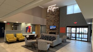 A lobby with a reception desk, seating area, and a TV screen. - Holiday Inn Express Harrisburg I-81 – Hershey by IHG (Harrisburg)