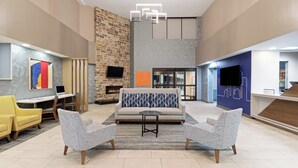 A spacious lobby with a modern fireplace, comfortable seating, and a reception desk. - Holiday Inn Express Harrisburg I-81 – Hershey by IHG (Harrisburg)