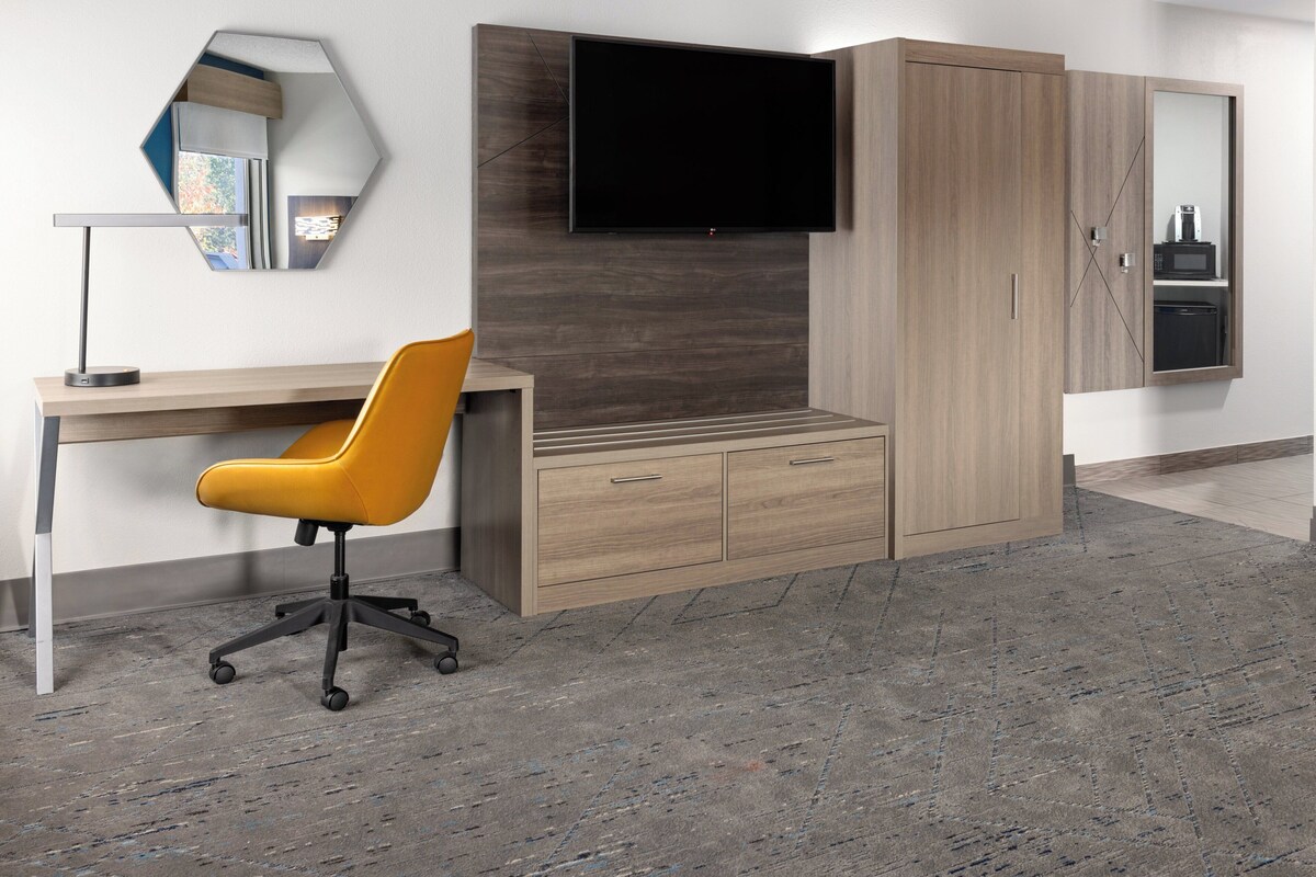 A modern office space with a desk, chair, and built-in TV.