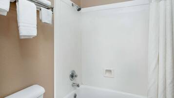 Un baño con bañera, un perchero con toallas blancas y una cortina de ducha.