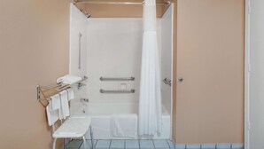 A bathroom with a walk-in shower, grab bars, a bench, and a towel rack.
