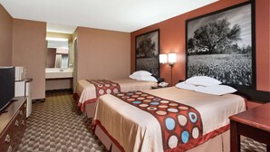 A hotel room with two beds, a desk, a television, and artwork on the walls.