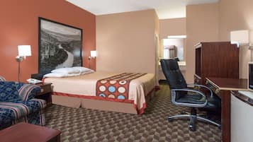 Een hotelkamer met een bed, een bureau, een stoel, een bank en een groot schilderij aan de muur.