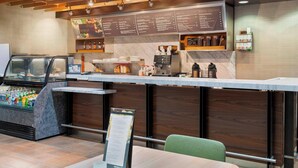 A modern café with a marble countertop, menu boards, and a coffee machine.